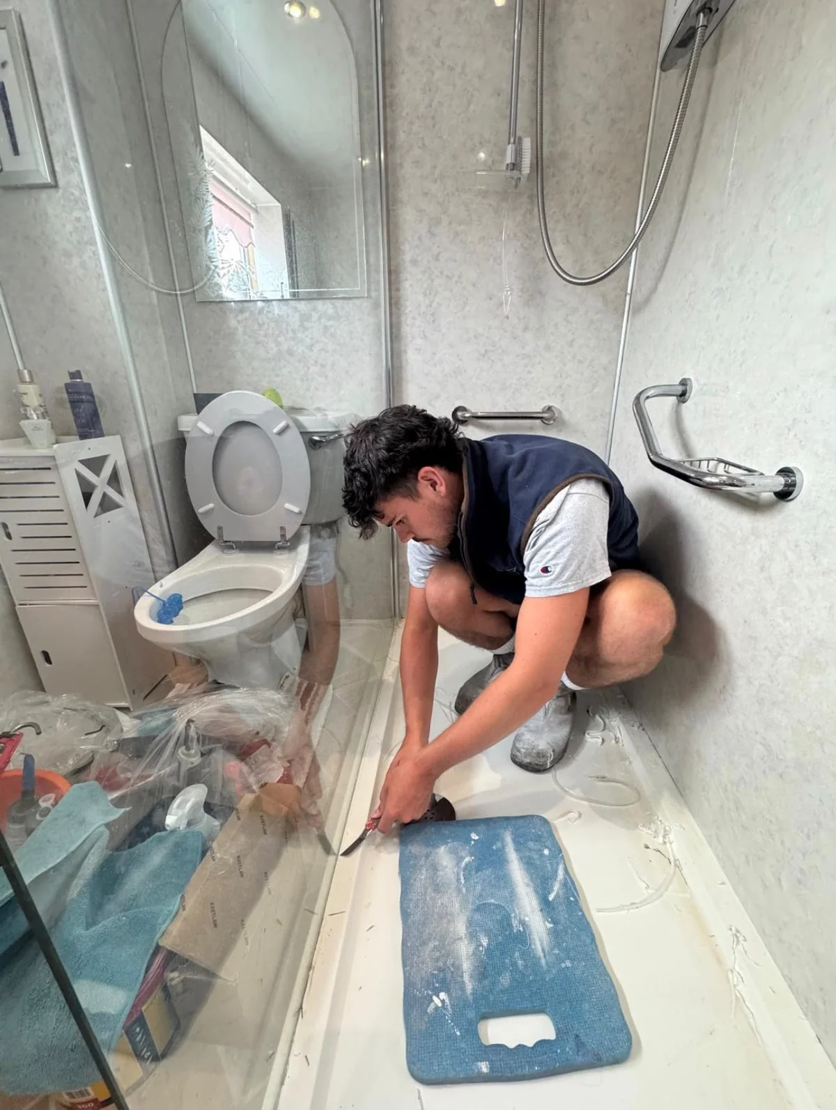 A team member preparing a shower tray for restoration